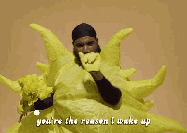 a man in a yellow costume is holding a bouquet of flowers and says you 're the reason i wake up