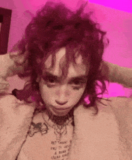 a girl with red hair and freckles is wearing a necklace and a white shirt .