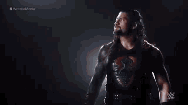 a wrestler is standing in front of a dark background with # wrestlemania written on it