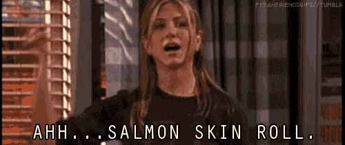 a woman says ahh salmon skin roll while standing in front of a window
