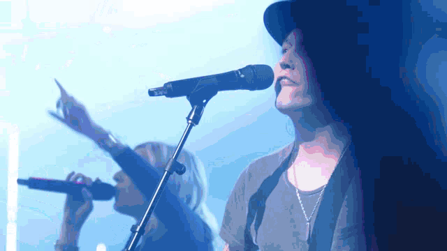 a man in a hat sings into a microphone while a woman sings behind him