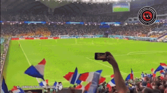 a person taking a picture of a soccer field with a logo that says ' alliance stadium ' on it