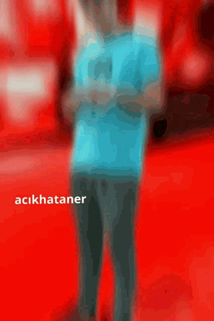 a man in a blue shirt is standing in front of a red background with the name acikhataner on the bottom