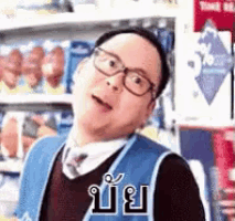 a man wearing glasses and a vest is standing in front of a shelf in a store .