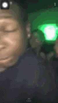 a close up of a person 's face with a green light in the background .