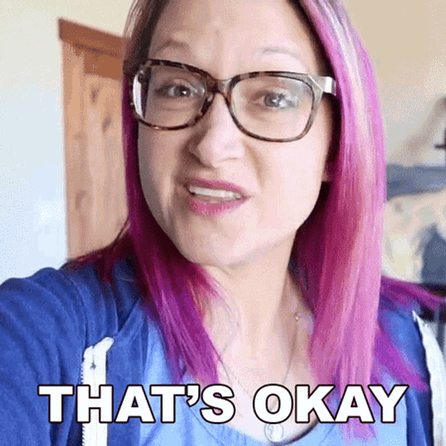 a woman with pink hair wearing glasses and a blue shirt says that 's okay .