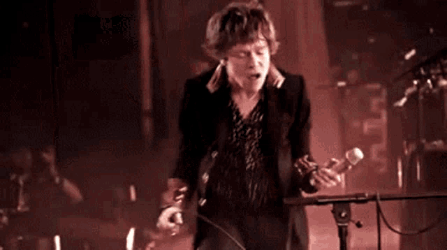 a man singing into a microphone while another man plays a guitar