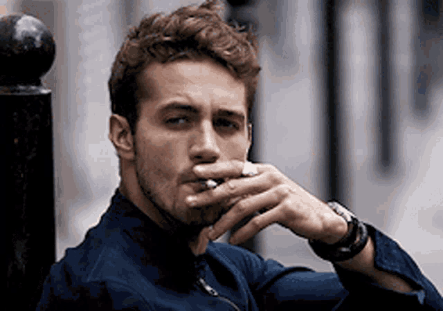 a man is smoking a cigarette with a ring on his finger