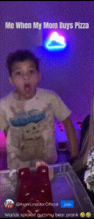 a young boy with a gummy bear on his shirt is standing in front of a pizza box ..