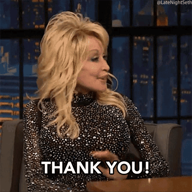 dolly parton is sitting at a table and saying " thank you "