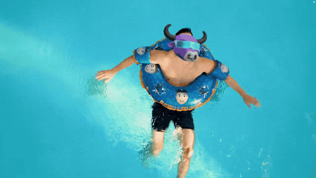 a man is swimming in a pool wearing a bull float with horns