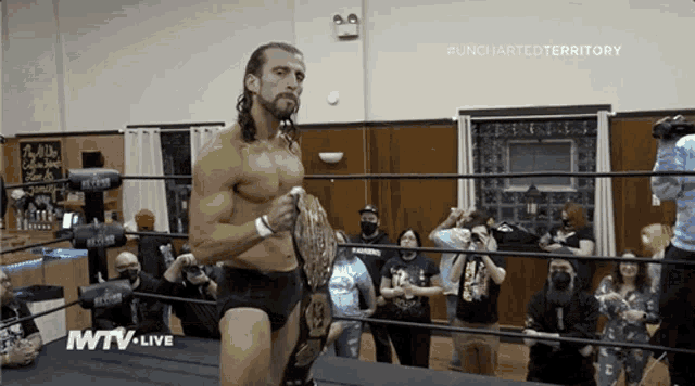 a man in a wrestling ring is holding a championship belt and says wtv live