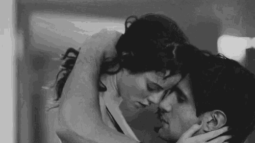 a black and white photo of a man and woman kissing each other .
