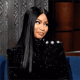 a woman with long black hair is sitting in a chair with her eyes closed and smiling .