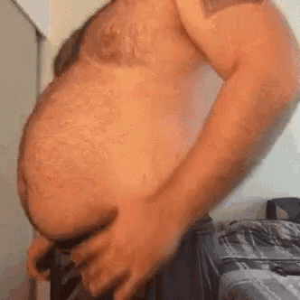 a shirtless man with a very large belly is standing in a room .