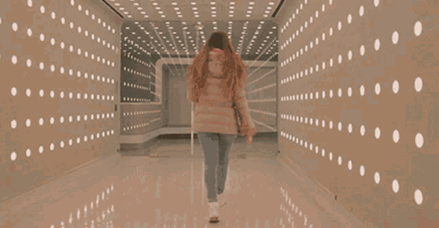 a woman is walking through a hallway with a sign on the wall that says ' aa '