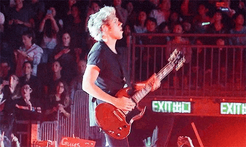 a man is playing a guitar on a stage in front of a crowd of people .