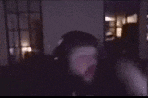 a man in a black hat is making a funny face in a dark room