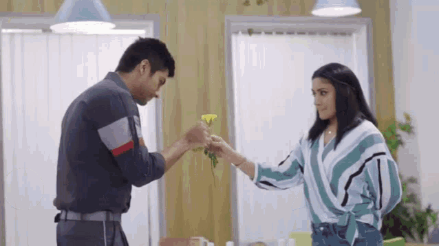 a man is giving a woman a yellow flower .