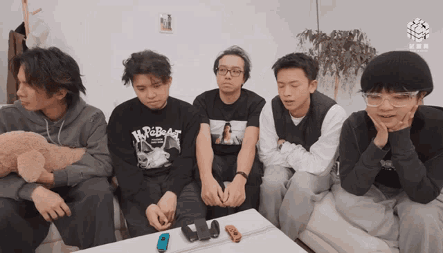 a group of young men are sitting around a table with one wearing a shirt that says n.p.o.beast