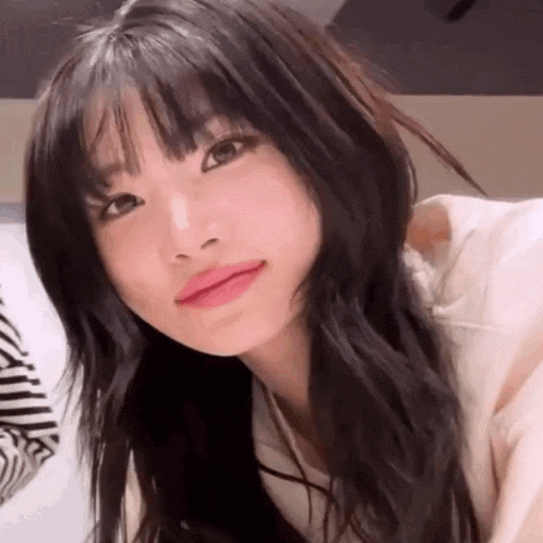 a close up of a woman 's face with long black hair and bangs .