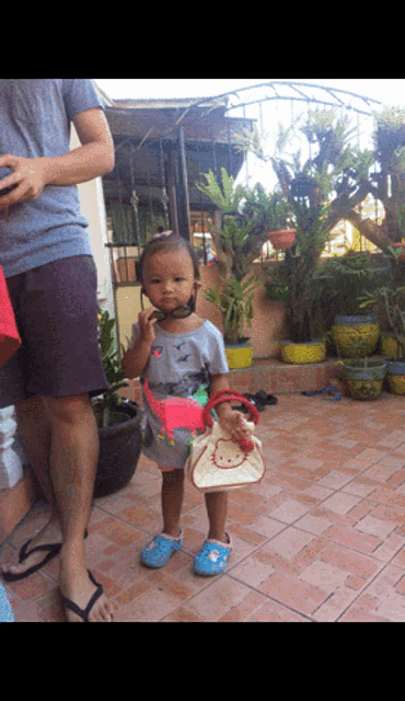 a little girl wearing a dinosaur shirt is holding a purse