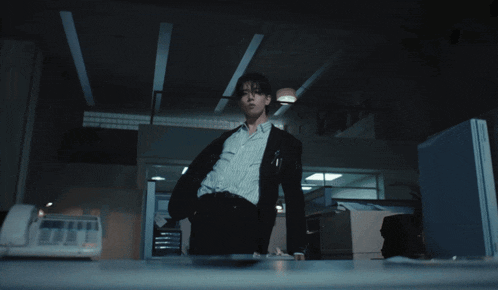 a man in a suit and striped shirt stands in an office