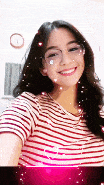 a girl wearing glasses and a striped shirt smiles