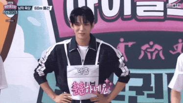 a young man stands in front of a sign that says ' mbc ' on it