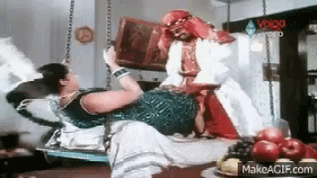a woman is laying on a man 's lap in a room with fruit on the table .