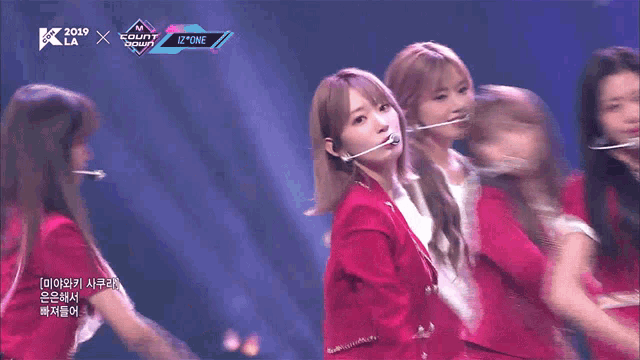 a group of girls are dancing on a stage with a banner that says izone on it