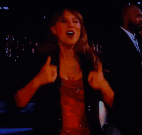 a woman in a red dress is dancing on a stage in front of a crowd