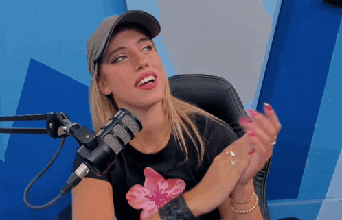 a woman sitting in front of a microphone with a hat on