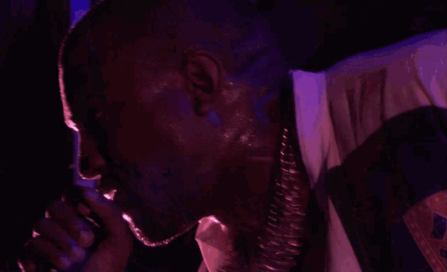 a man is singing into a microphone with purple lights behind him