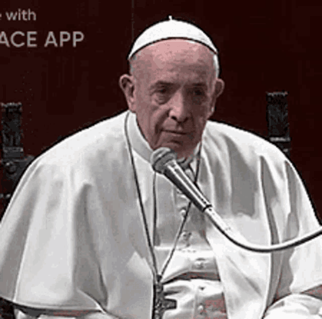 a man in a white robe is sitting in front of a microphone with the words peace app behind him