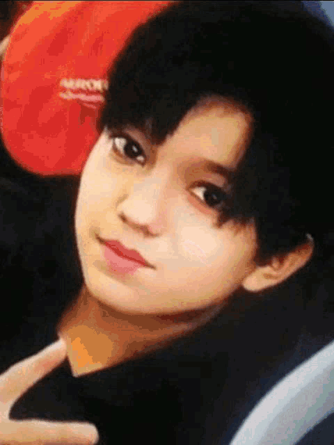 a close up of a young boy 's face with a red bag in the background