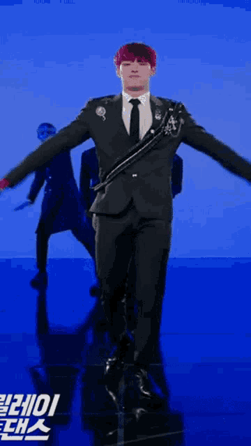 a man in a suit and tie is dancing in front of a blue background