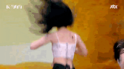 a woman in a white tank top is dancing in front of a wall that says jtbc on it