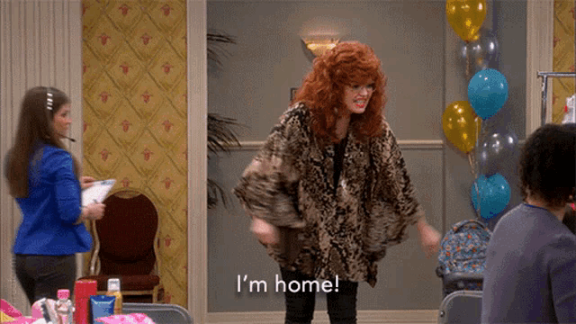 a woman in a fur coat says i 'm home in front of balloons