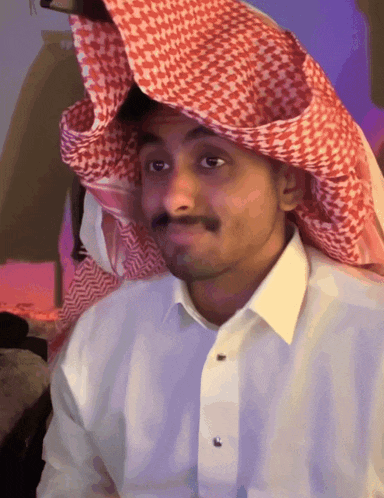a man wearing a white shirt and a red and white checkered scarf on his head