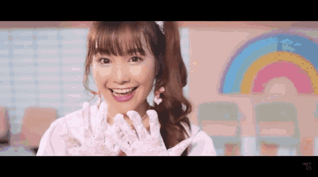 a girl wearing white lace gloves is smiling in front of a colorful rainbow