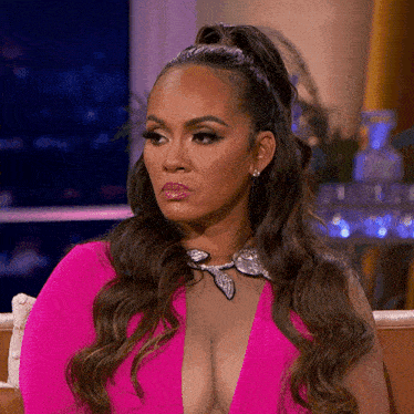 a woman in a pink dress is sitting on a couch and looking at the camera