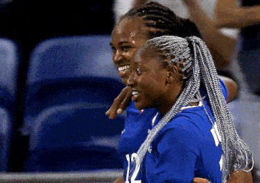 two women wearing blue jerseys with the number 12 on the front
