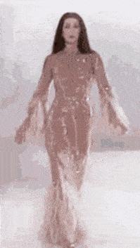 a woman is walking down a runway in a long dress .