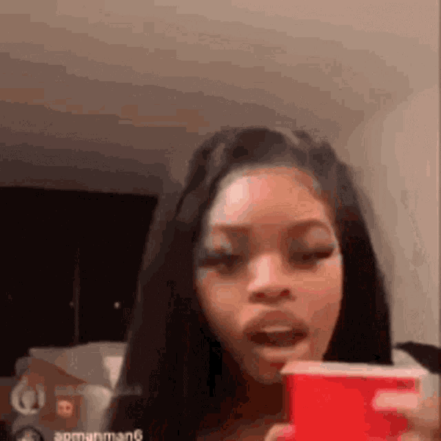 a woman is holding a red cup in her hand while talking on a cell phone .