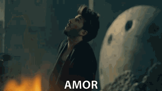 a man is standing in front of a fire and the word amor is on the bottom right