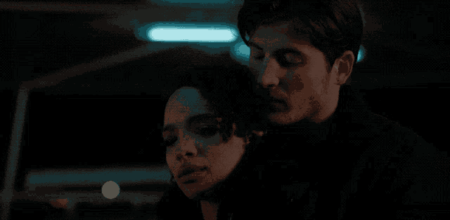 a man and a woman are looking at something in the dark