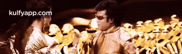 a man and a woman are standing next to each other in front of a crowd of gold soldiers .