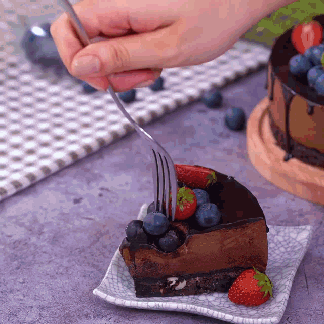 a piece of chocolate cake with blueberries and strawberries on a plate