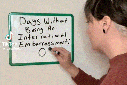a woman is writing on a whiteboard that says days without being an international embarrassement